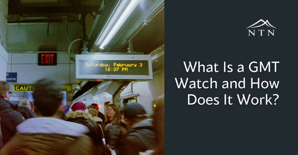 People standing in a crowded underground train platform with a digital clock display.